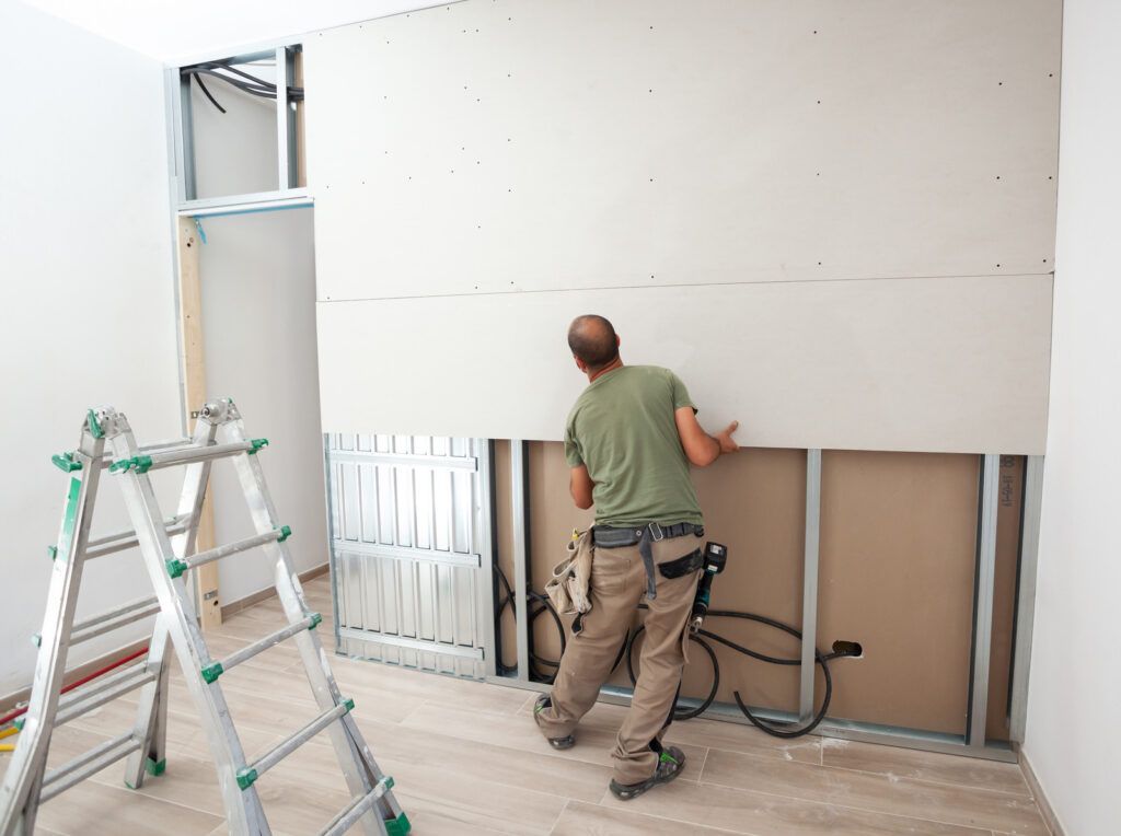 worker installing soundproof plasterboard